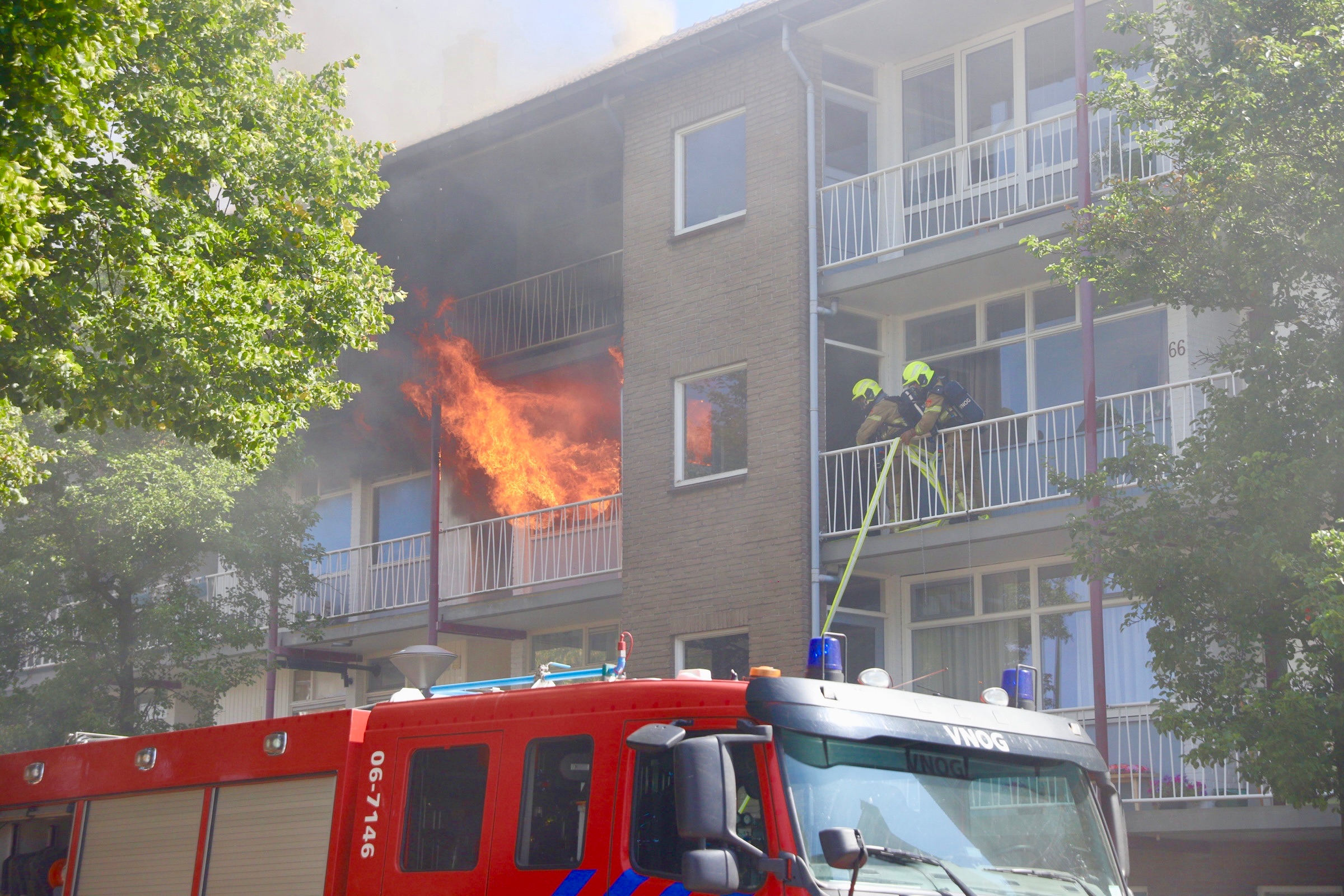 Grote uitslaande brand in flatgebouw; vlammen slaan fel uit woning en explosie gemeld